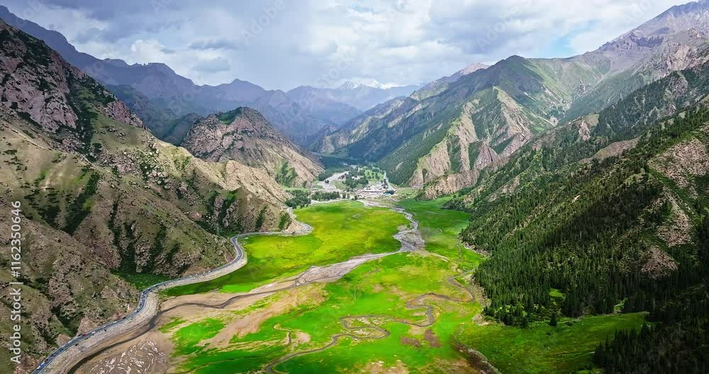 Aerial view of green meadow and mountain range nature landscape in summer. Beautiful scenery along the Duku Highway in Xinjiang, China. Aerial view of green meadow and mountain range nature landscape in summer. Beautiful scenery along the Duku Highway in Xinjiang, China.
