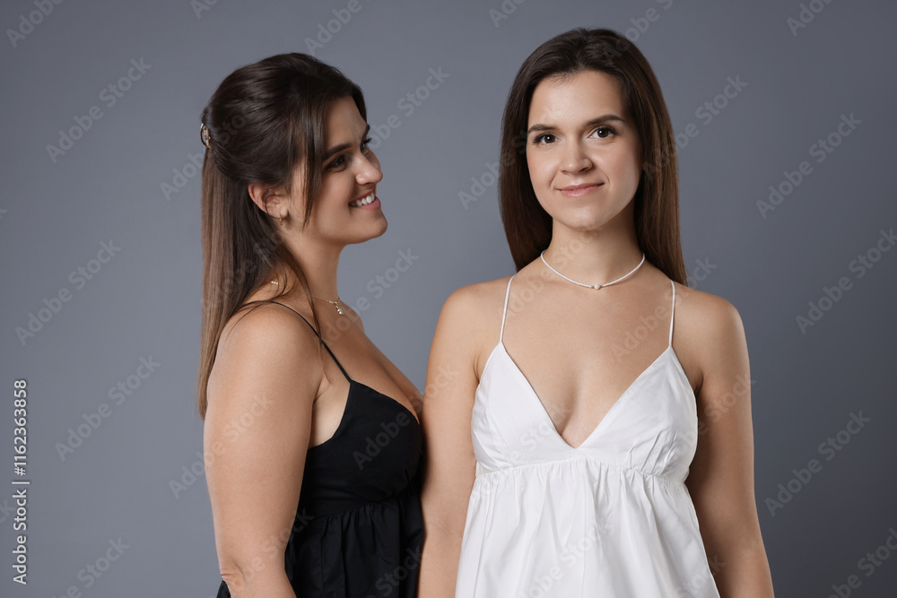 Portrait of beautiful twin sisters on grey background Portrait of beautiful twin sisters on grey background