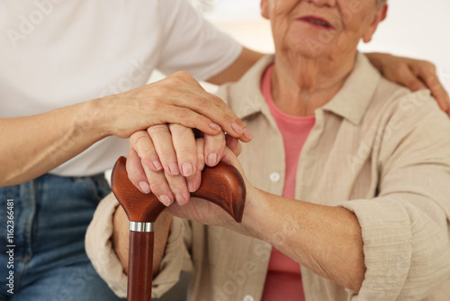 Caregiver supporting senior woman at home, closeup