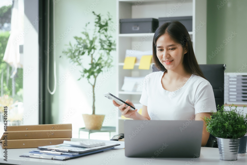 An Asian businesswoman works at her desk in a modern office, smiling while using a tablet to review financial analysis reports, manage accounting tasks, and oversee banking and loan documentation An Asian businesswoman works at her desk in a modern office, smiling while using a tablet to review financial analysis reports, manage accounting tasks, and oversee banking and loan documentation