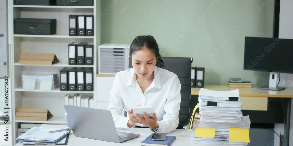 An Asian businesswoman sits at her desk in the office, working on her laptop, checking documents, and planning business strategies to enhance productivity and achieve professional goals An Asian businesswoman sits at her desk in the office, working on her laptop, checking documents, and planning business strategies to enhance productivity and achieve professional goals