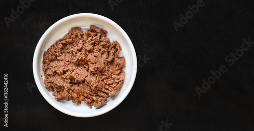 Cat food, pate, top view. Canned food for pets in a round white plate on a dark background. Tasty and healthy food for domestic cats. A portion of wet food, soft pate for a cat on a plate. Copy space