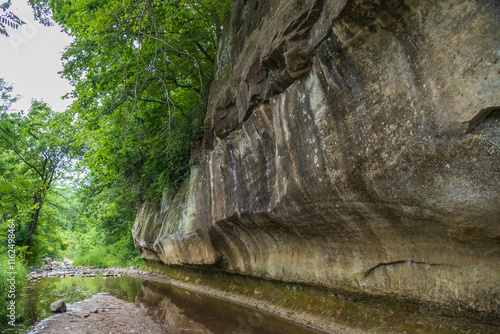 Sandstone ledge, trees and a creek in nature park in Iowa; concepts of nature lover, tranquility and outdoor adventure
