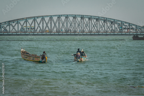 Obraz na płótnie Typical senegalese fishermen with boats called pirogue floating towards famous faidherbe metal bridge over senegal river. Beautiful african postcard.. w salonie