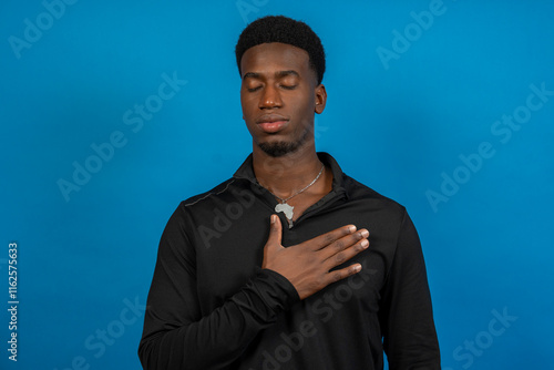 Canvas Print Young man pledging allegiance with hand on chest and closed eyes
