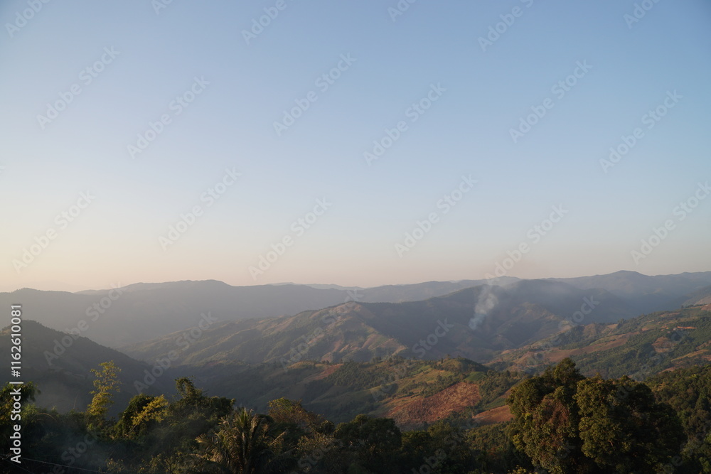 Naklejka premium Landscape of Morning Mist with Mountain Layer at north of Thailand. mountain ridge and clouds in rural jungle bush forest.