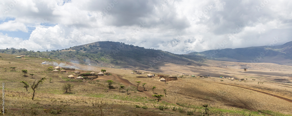 Naklejka premium Scenic view of traditional Masai village surrounded by mountains in Serengeti Tanzania East Africa