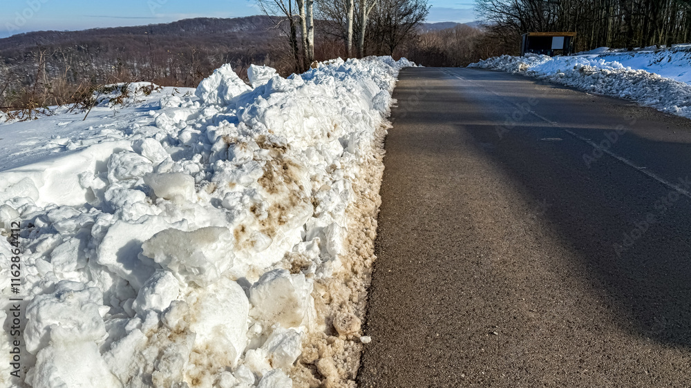 A snow-covered rural road in winter highlights transportation challenges and the beauty of nature during the Christmas season A snow-covered rural road in winter highlights transportation challenges and the beauty of nature during the Christmas season