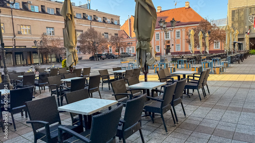 An empty outdoor cafe in a European city square captures urban solitude and the impact of seasonal weather changes photo