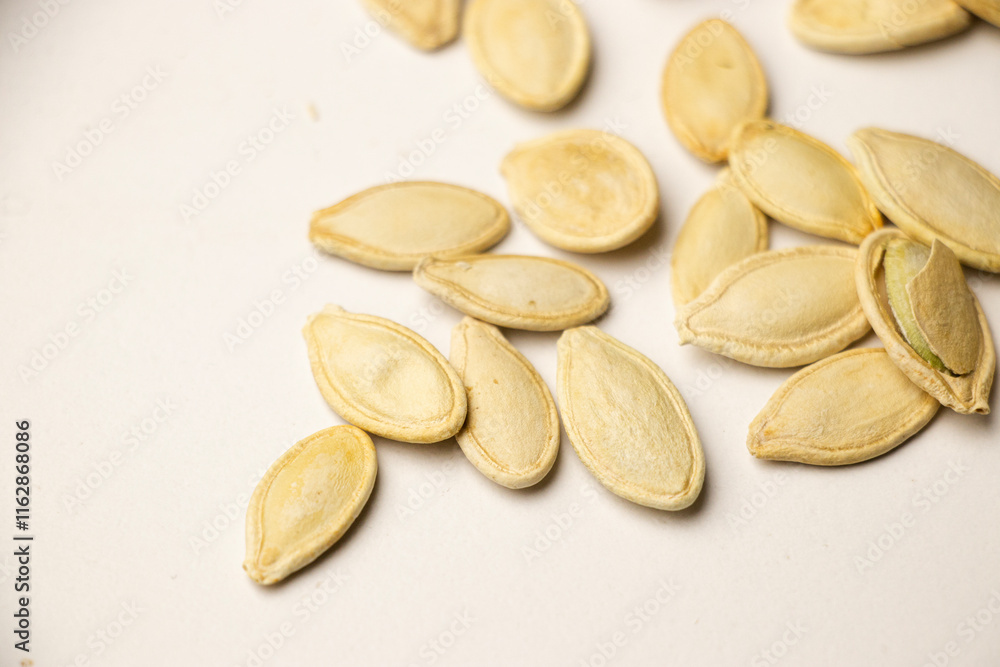 A handful of pumpkin seeds displayed against a white , emphasizing their natural texture, nutritious appeal, and suitability for healthy eating or cooking concepts A handful of pumpkin seeds displayed against a white , emphasizing their natural texture, nutritious appeal, and suitability for healthy eating or cooking concepts