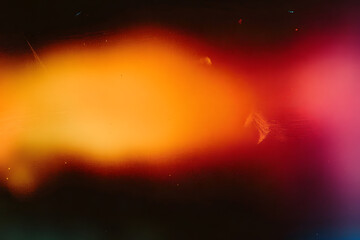 Blur colorful warm rainbow light leaks on black background with dust texture. Defocused abstract damaged scratched retro film analog effect for using over photos as overlay or screen filter