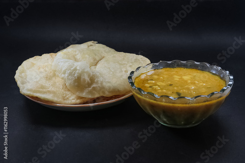 Homemade Daalpuri with Sweet Chana Daal. Oil fried puffed flat bread made with healthy wheat flour and chana masala served in a steel plate and glass bowl. Indian cuisine. photo