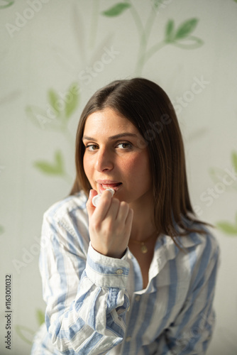 The girl in shirt puts a lip balm on her lips photo