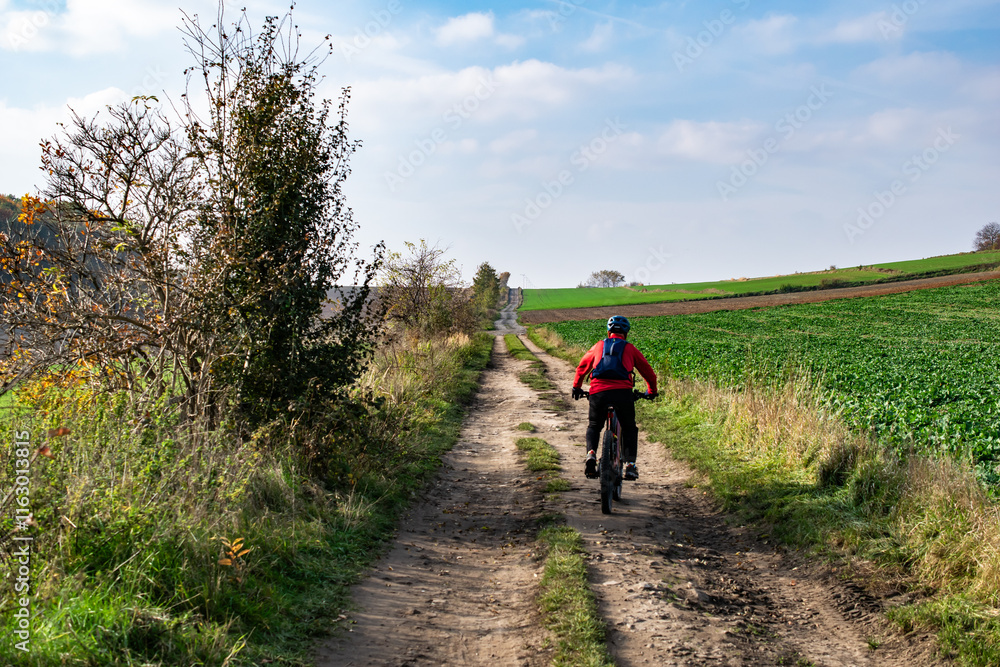 man riding a bicycle on a dirt road man riding a bicycle on a dirt road