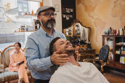 Photos barber shop concept and people - Barber applying aftershave to a man's face in a