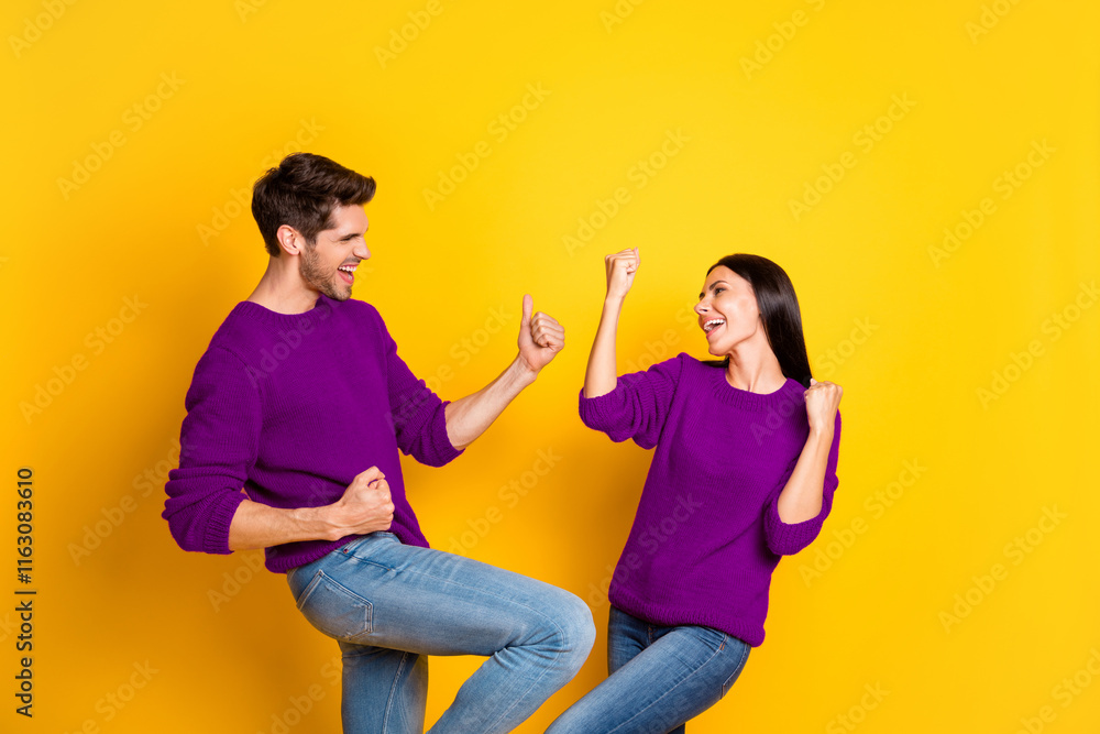 Obraz premium Portrait of delighted two married people raise fists scream yeah celebrate victory wear red sweater denim jeans isolated over yellow background