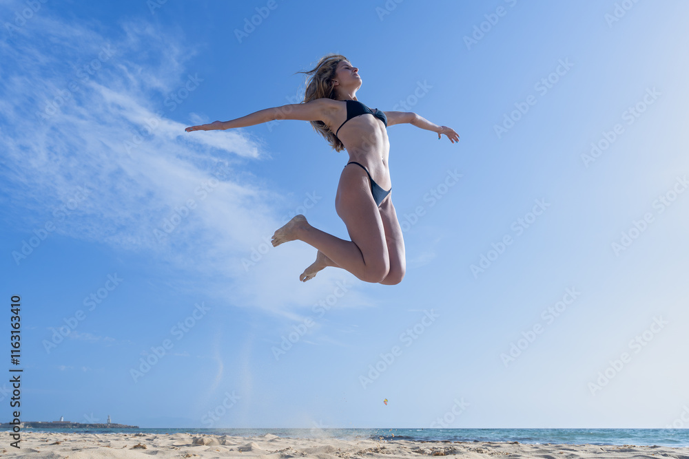 Mujer joven saltando de emoción porque esta muy a gusto, con un sensacional día de vacaciones en verano soleado con cielo azul. Mujer joven saltando de emoción porque esta muy a gusto, con un sensacional día de vacaciones en verano soleado con cielo azul.