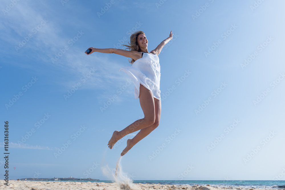 Mujer joven saltando de emoción porque esta feliz y divertida, con un sensacional día de vacaciones en verano en la playa, soleado con cielo azul. Mujer joven saltando de emoción porque esta feliz y divertida, con un sensacional día de vacaciones en verano en la playa, soleado con cielo azul.