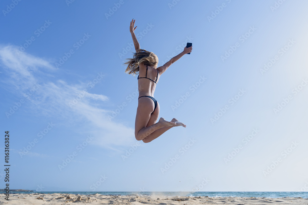 Mujer joven saltando de emoción porque esta feliz y divertida, con un sensacional día de vacaciones en verano en la playa, soleado con cielo azul. Mujer joven saltando de emoción porque esta feliz y divertida, con un sensacional día de vacaciones en verano en la playa, soleado con cielo azul.