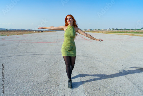 Obraz na płótnie Mujer con con los brazos abiertos en una pista de aterrizaje de un aeropuerto soñando despierta que ya esta volando hacia su destino un día soleado con cielo azul