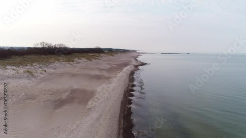 Drone flies forward over Nida Beach, calm Baltic shoreline on cloudy day, Latvia photo