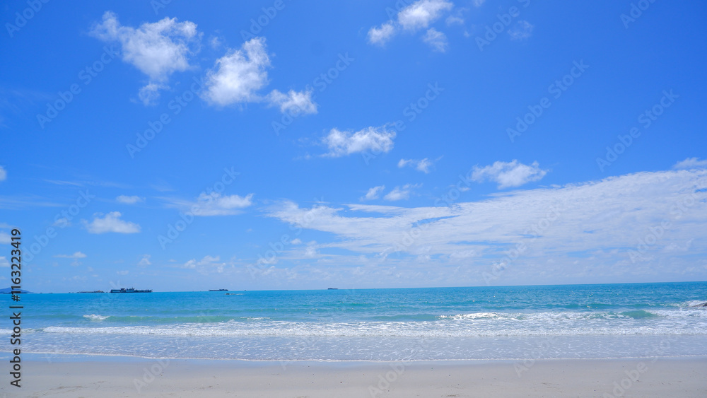 A serene tropical beach with soft white sand, turquoise water, and clear blue skies dotted with fluffy white clouds A serene tropical beach with soft white sand, turquoise water, and clear blue skies dotted with fluffy white clouds