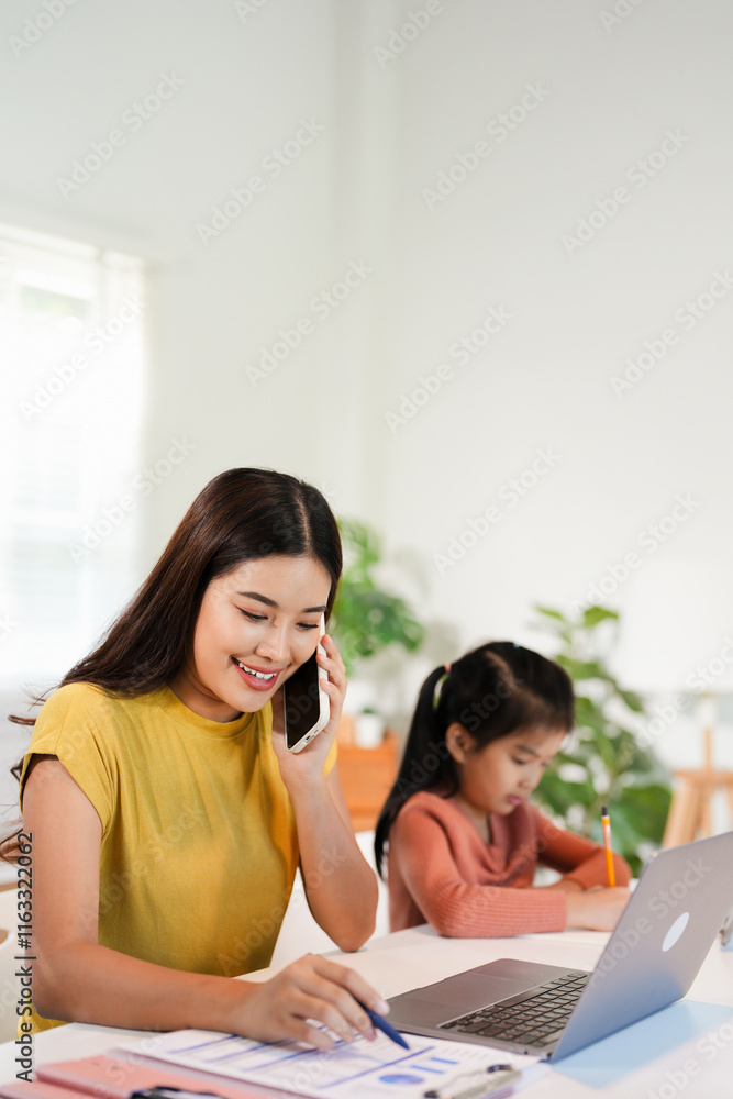 Concept of work from home and home family education. Mom and daughter are sitting at the desk. Business woman works on the Internet in a laptop, a child writes in a notebook. Concept of work from home and home family education. Mom and daughter are sitting at the desk. Business woman works on the Internet in a laptop, a child writes in a notebook.