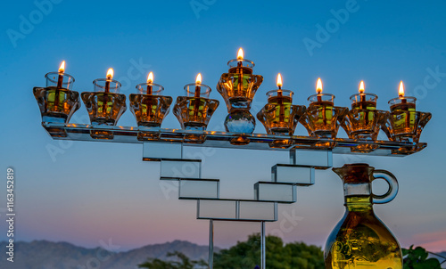 Crystal festive menorah and burning olive oil in decorative jar candles. Main...