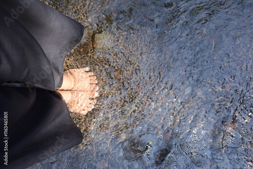 top view of feet soaking in fresh flowing water, Feet in cold clear and clean water feel relaxed and fresh, Relaxing by the sea. Barefoot woman's feet standing in water.