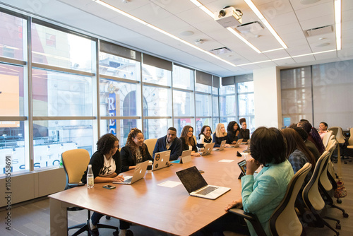 A modern meeting room with a long wooden table, ergonomic chairs, and large windows providing natural light. Equipped with a projector, minimalist décor, and a professional atmosphere.