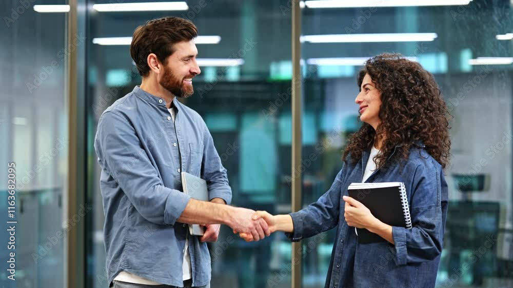 Two happy businesspeople shaking hands in a friendly greeting. Business man and woman shaking hands in modern office. Friendly greeting in workplace. Two happy businesspeople shaking hands in a friendly greeting. Business man and woman shaking hands in modern office. Friendly greeting in workplace.