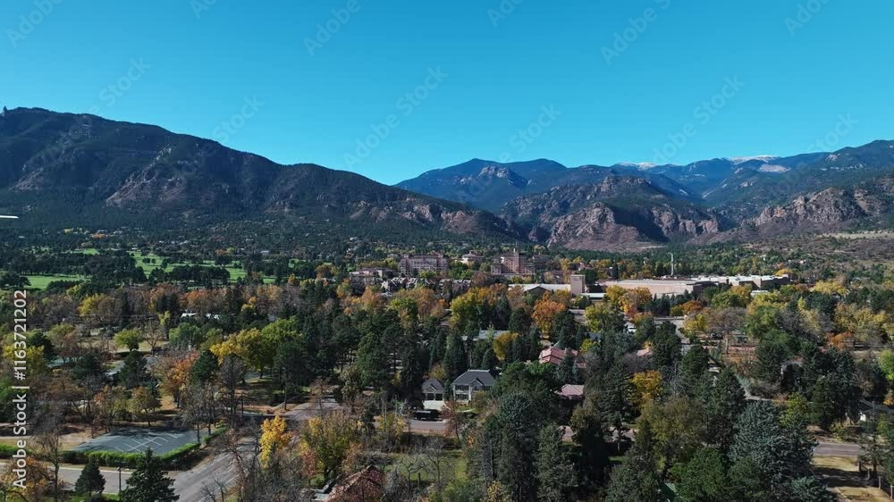 Aerial establishing across Colorado Springs with vibrant fall foliage and hotel building centered in distance