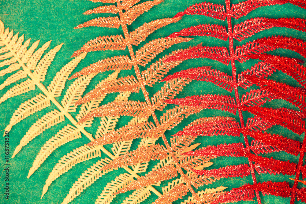 Colorful artificial fern leaves on a green background