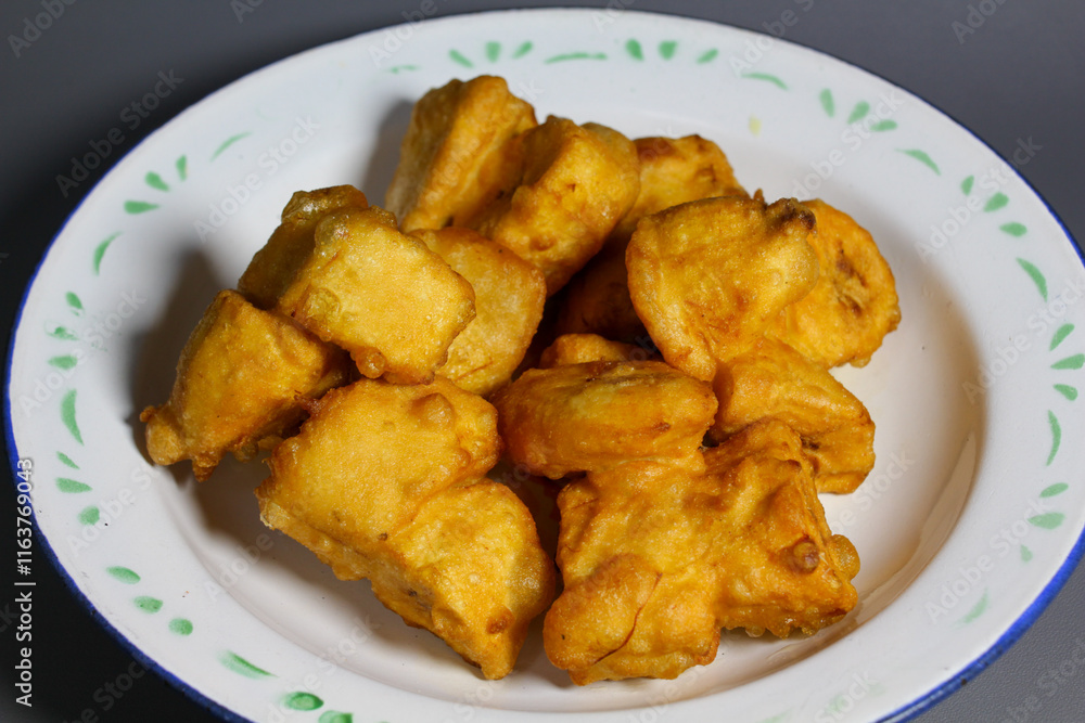 Crispy golden fritters banana served on a white plate with green accents during a festive gathering Crispy golden fritters banana served on a white plate with green accents during a festive gathering