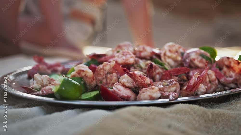 People eat delicious grilled shrimp served on plate with lime, cherry and sliced cucumber. Cheerful beach vibes in summer. Close up shot in slow motion People eat delicious grilled shrimp served on plate with lime, cherry and sliced cucumber. Cheerful beach vibes in summer. Close up shot in slow motion