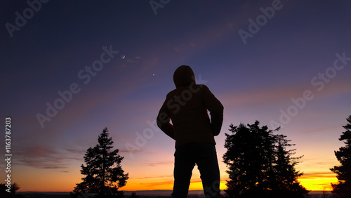 Silhouette of a man observing Milky Way stars from a dark countryside location..