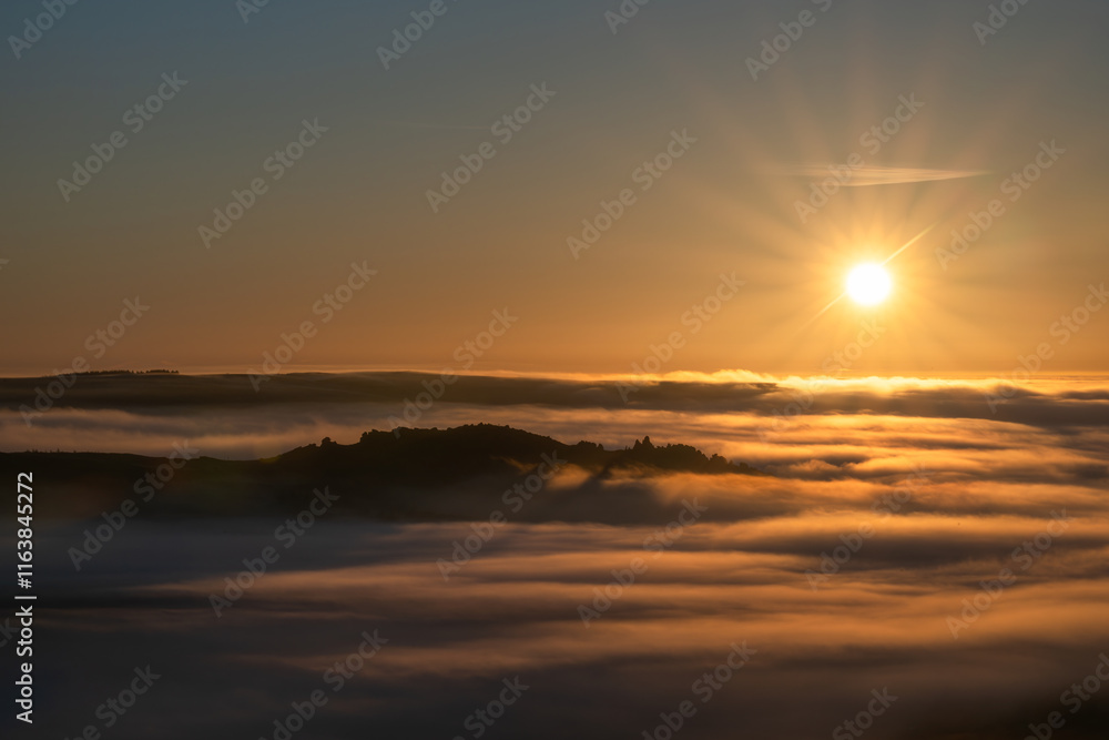 Obraz premium A rural sunrise winter landscape of Ramshaw Rocks shrouded in mist and fog during a cloud inversion in the Staffordshire Peak District National Park, England, UK.