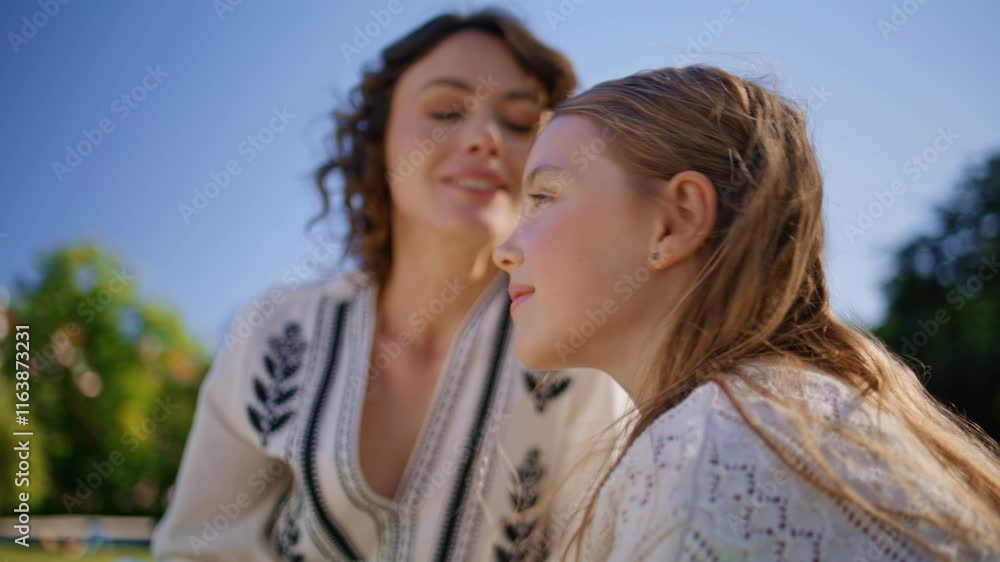 Mother child sitting park closeup. Smiling mom daughter resting nature portrait