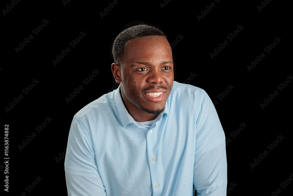 Smiling man in light blue shirt against a black background. Smiling man in light blue shirt against a black background.