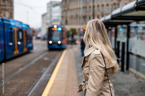 Businesswoman with blond hair standing at tram station