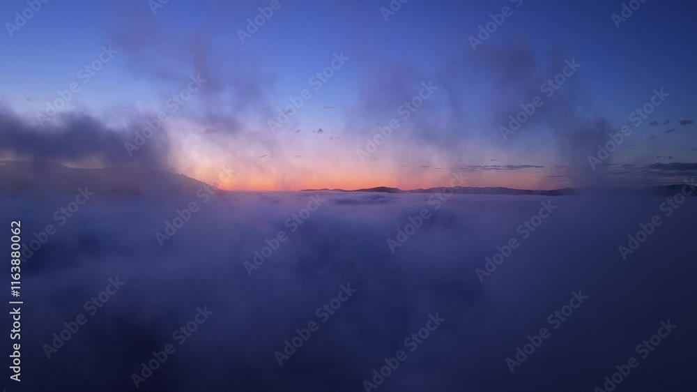 Dawn breaks over majestic mountain peaks surrounded by a sea of clouds revealing stunning natural beauty