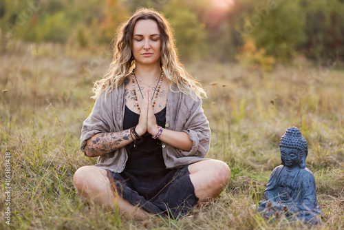 Smiling woman meditating near Buddha statue photo