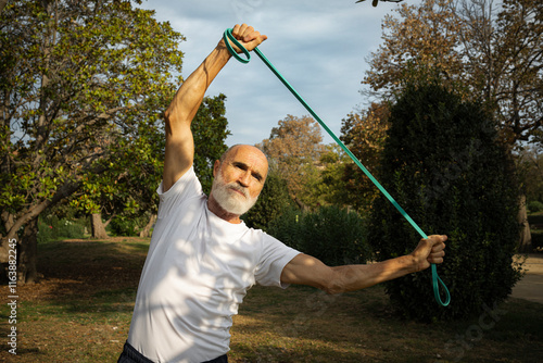 Senior man exercising with resistance band in park photo