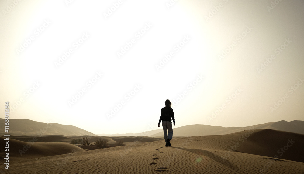 silhouette of a woman walking on the sand through the dersert silhouette of a woman walking on the sand through the dersert
