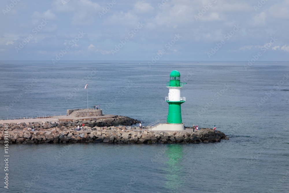 Green lighthouse at Westmole (Molenfeuer Warnemunde) in Rostock with unrecognizable people
