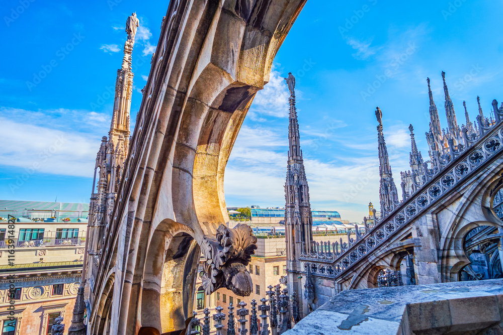 The view through the stone decorative elements on the roof of Milan Cathedral, Italy