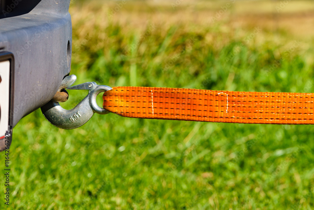 Fototapeta premium Tow hook with orange strap on car. Towing equipment.