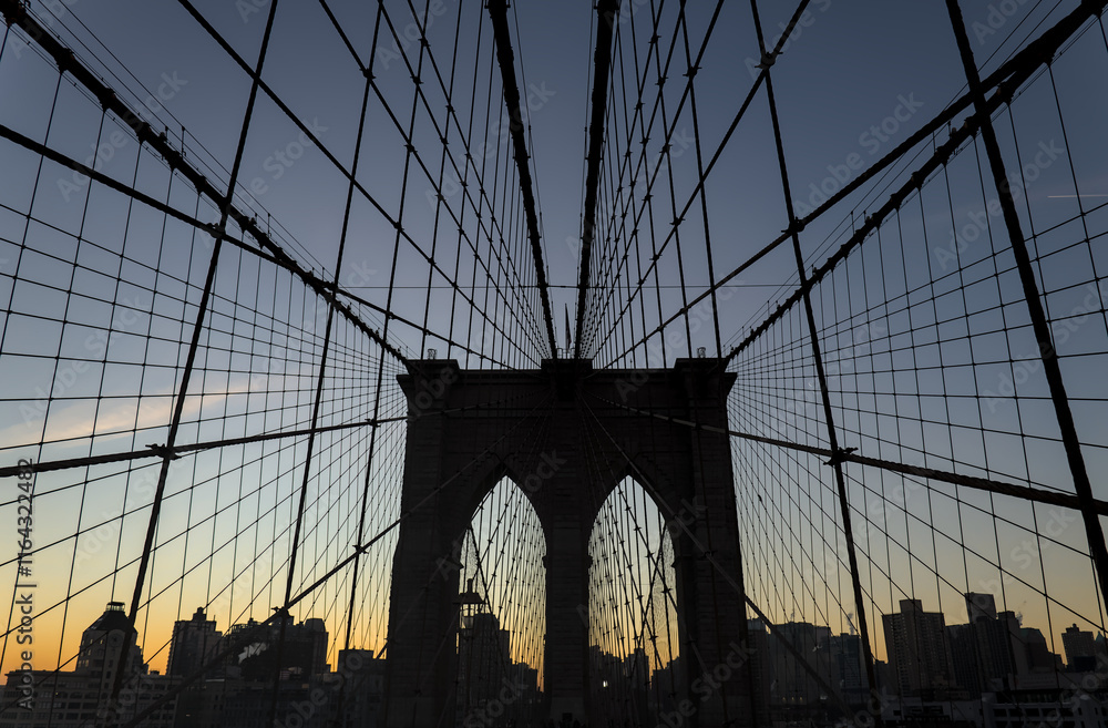Obraz premium Brooklyn Bridge close up detail looking up at suspension cables at sunrise (beautiful landmark travel tourism destination in NYC) iconic New York City attraction over east river downtown Manhattan USA