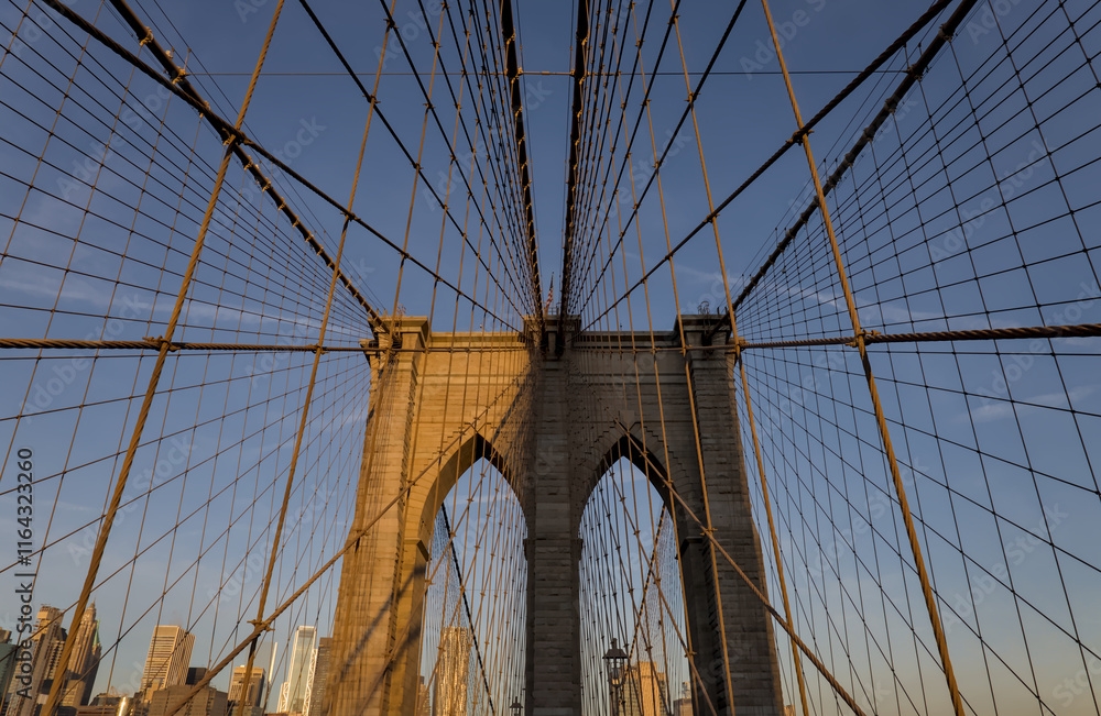 Fototapeta premium Brooklyn Bridge close up detail looking up at suspension cables at sunrise (beautiful landmark travel tourism destination in NYC) iconic New York City attraction over east river downtown Manhattan USA