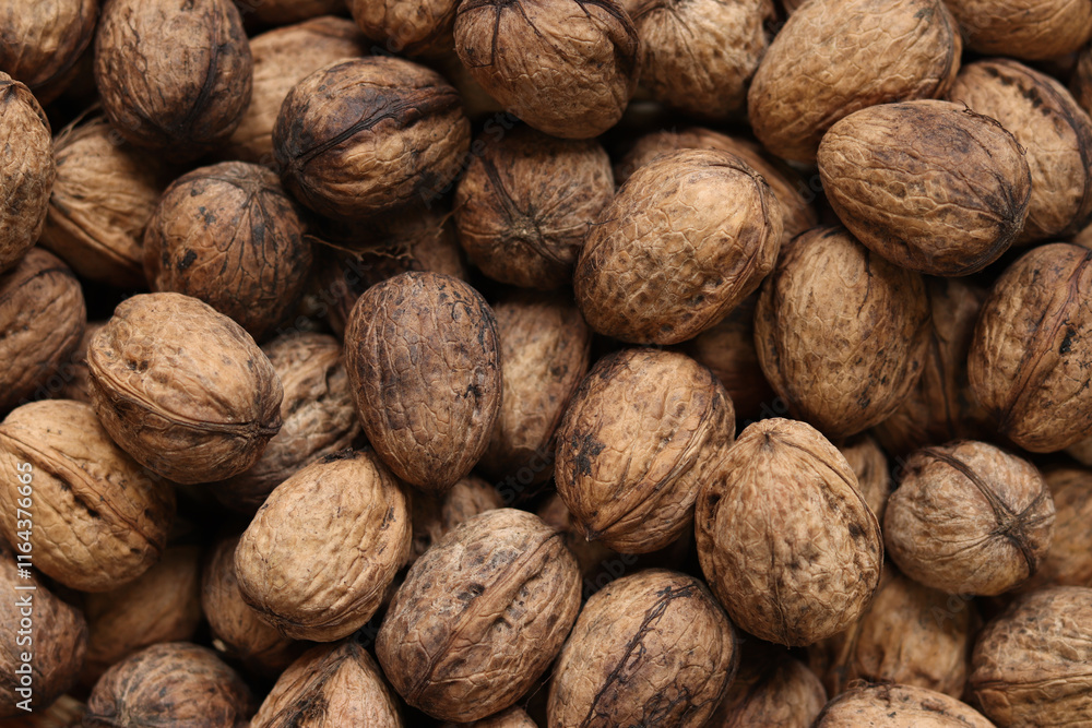 Heap of walnuts in shell, close-up, top view. Healthy eating. Harvest, agriculture. Walnuts, selective focus, background Heap of walnuts in shell, close-up, top view. Healthy eating. Harvest, agriculture. Walnuts, selective focus, background